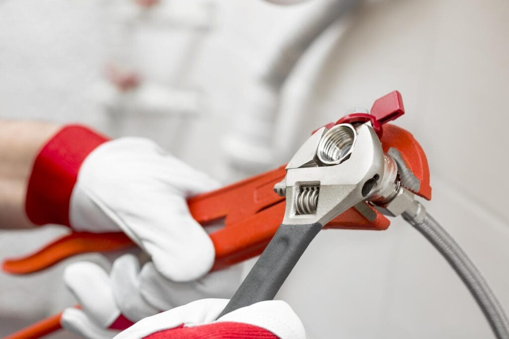 Plumber holding pipe wrenches for an emergency repair in Littleton