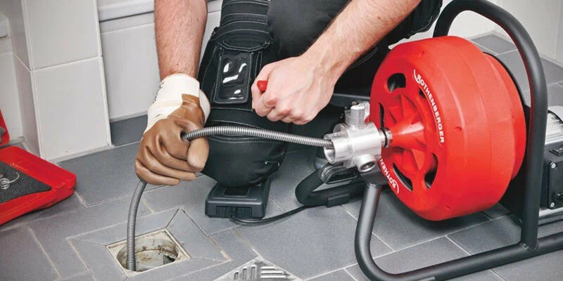 Plumber using a drain-cleaning machine in Littleton